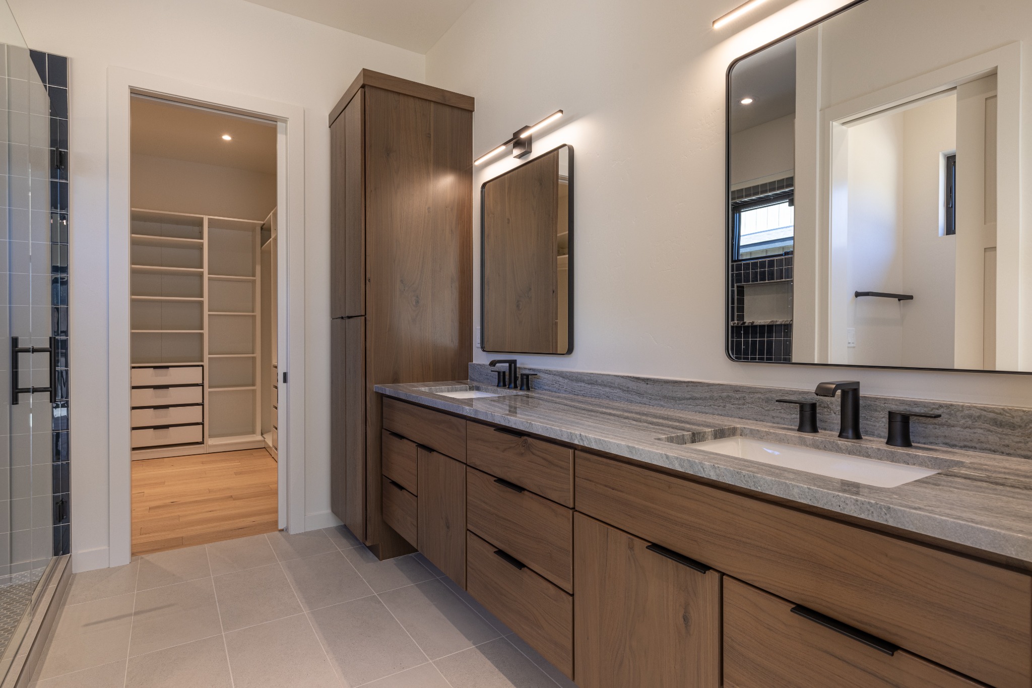 Bathroom with double vanity, wood cabinetry, and walk-in closet
